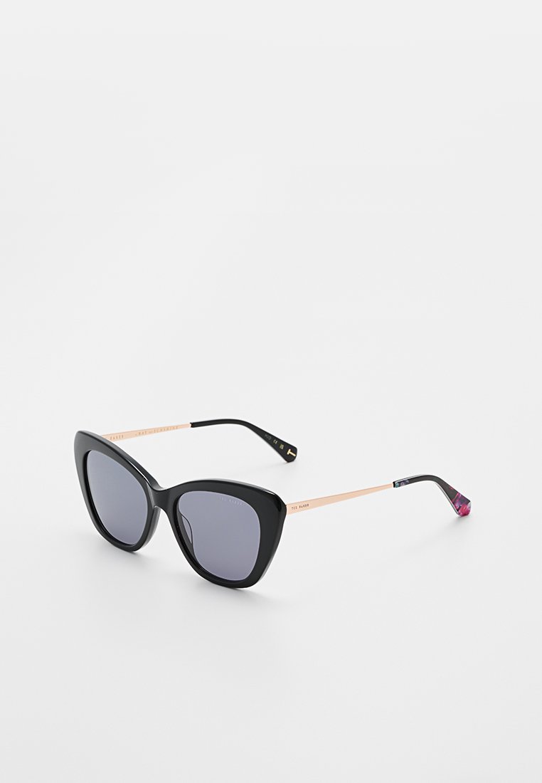 Black cat-eye sunglasses with gradient gray lenses, rose gold metal arms, and patterned tips. Features bold, angular design and dark finish.