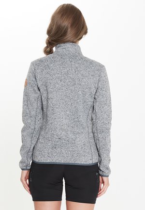 Veste en polaire grise texturée avec un col haut, un design ajusté et des manches longues. Présente un patch logo sur l'épaule gauche.