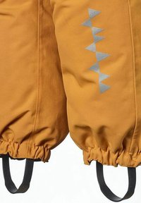 Vattenavvisande, senapsgul tyg med elastiska ärmar, prydd med ett reflekterande silvertriangulärt mönster längs sidan och svarta remmar.