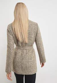 Długi kardigan z mieszanki wełny w wzór jodełkowy, w odcieniach beżowych i brązowych, z paskiem w talii, długimi rękawami i miękką fakturą.