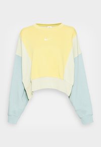 Kleurgebroken Nike sweatshirt met een gele borst, crèmekleurige bovenmouwen en lichtblauwe ondermouwen, met een wit Nike-logo aan de voorkant.