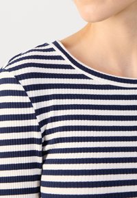 Gestreiftes Langarmoberteil mit marineblauen und weißen horizontalen Streifen, runden Ausschnitt und weicher Textur, das ein lässiges Design betont.