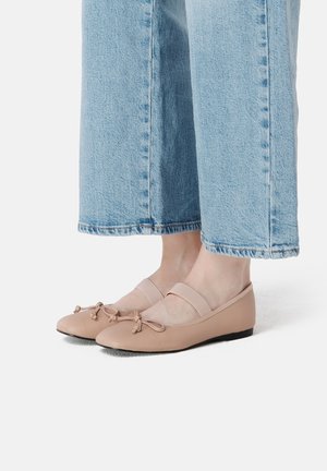 Ballerines en cuir nude à bout arrondi, bride élastique et nœuds décoratifs, associées à un pantalon en jean raccourci.