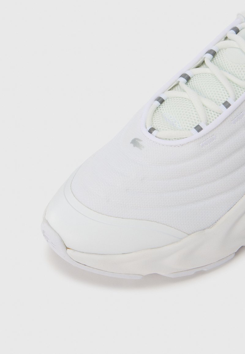 Witte sportschoen met een gestructureerd bovenwerk van gaas, voorzien van lichtgrijze accenten en een afgeronde neus. Veters geïntegreerd in een gestructureerd ontwerp.