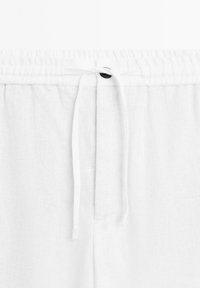 Pantalon en lin blanc avec taille élastique, fermeture à cordon et un bouton unique à l'avant. Texture douce et légère.