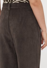 Brune kordfløyelsbukser med vertikale ribber, med rett snitt, middels høy midje og flat frontdesign.