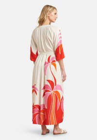 Maxi dress in light cream fabric with vibrant red, pink, and orange flower patterns, featuring three-quarter sleeves and a gathered back.