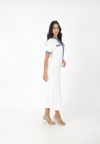 Weißes geripptes Kleid mit kurzen Ärmeln und Denim-Akzenten, mit einer durchgehenden Knopfleiste und gerader Silhouette. Klare Blockabsatzsandalen.