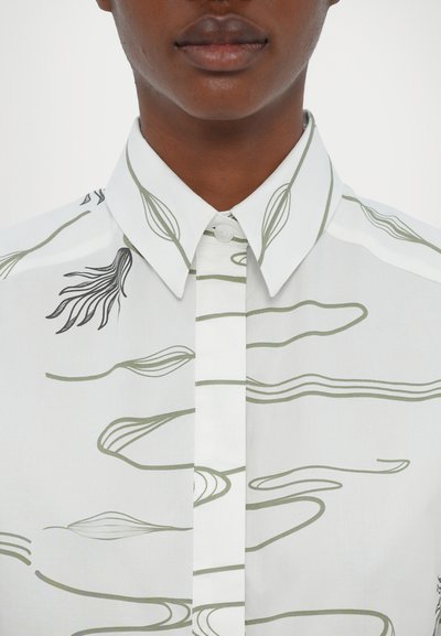 White button-up shirt featuring green abstract line patterns and black accents along the collar and placket. Smooth fabric texture.