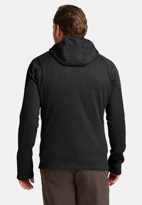 Giacca in pile nera con cappuccio e finitura testurizzata, caratterizzata da un design senza maniche sulle spalle e maniche lunghe, indossata da una persona vista da dietro.