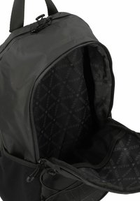 Sac à dos noir avec une ouverture zippée, présentant un extérieur lisse et un intérieur en tissu de marque. Comprend une poche en mesh et des sangles réglables.