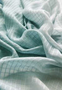Tissu bleu clair avec une surface douce et texturée, présentant un motif de grille subtil tissé dans l'ensemble.