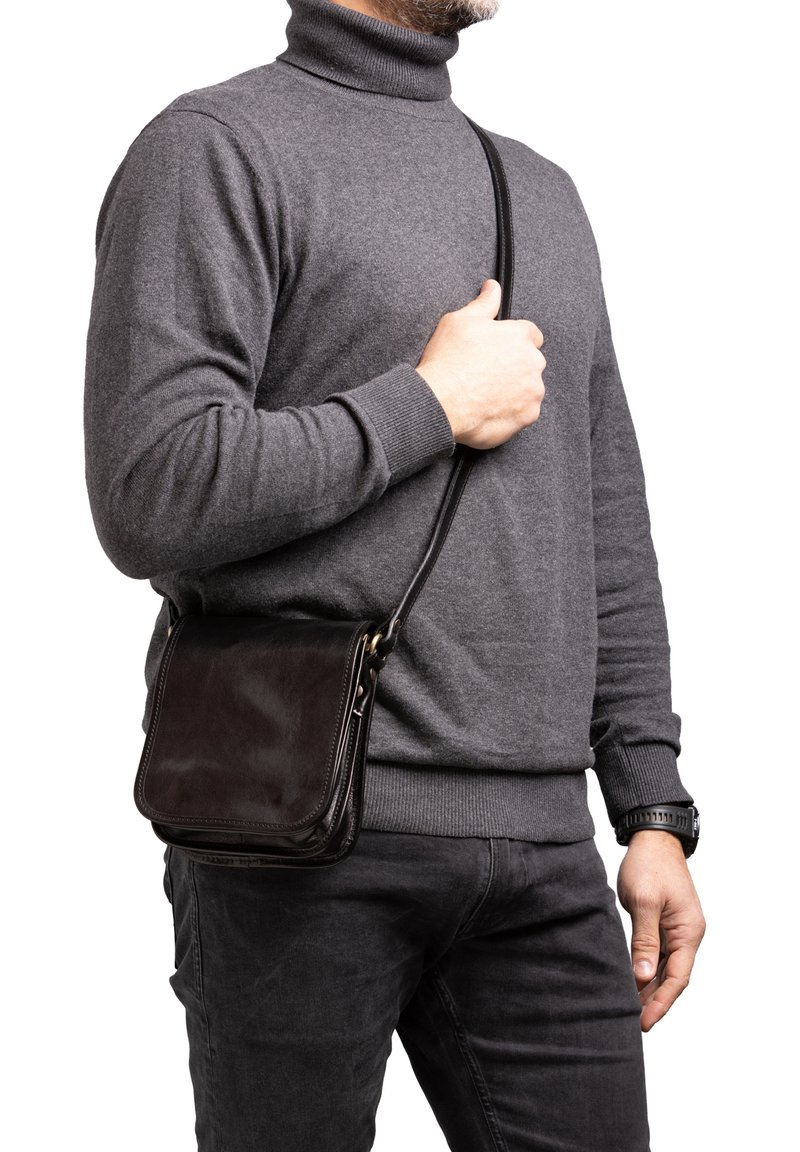 Borsa a tracolla in pelle marrone con finitura liscia, forma rettangolare, tracolla staccabile e design minimalista, indossata su un maglione grigio.