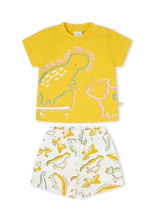 Camiseta amarilla para niño pequeño con dinosaurio y texto “Ven y únete a nosotros,” combinada con pantalones cortos blancos con coloridos dinosaurios en monopatines.