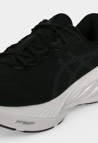Gros plan d'une chaussure de sport noire avec lacets noirs, côté gris à motifs et semelle blanche épaisse portant la marque FF Blast+.