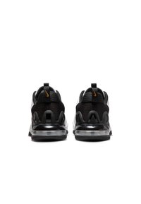 Zapatillas Nike en blanco y negro con parte superior de malla, suela de aire transparente y acentos en naranja contrastante. Cuenta con un collar acolchado y un diseño de suela robusto.
