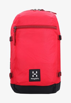 Mochila roja hecha de un tejido duradero. Presenta un bolsillo frontal con cremallera, un fondo negro, tirantes ajustables y una etiqueta de logo en la parte frontal.