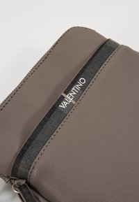 Brown nylon pouch with a textured surface, featuring a black striped accent with "VALENTINO" logo in silver. Zipper closure along the top.