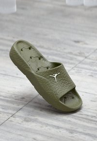 Πράσινο λαστιχένιο σανδάλι με υφή στην επάνω πλευρά και λευκή λογότυπο. Περιλαμβάνει ανοιχτή σχεδίαση μπροστά και σχηματισμένο σόλα για άνεση.