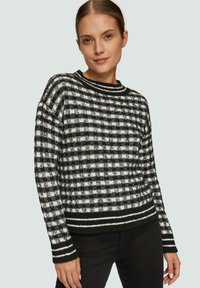 Zwart-wit geblokt gebreid sweater met lange mouwen, geribbelde ronde hals, en contrasterende gestreepte onderrand. Zachte textuur, losse pasvorm.