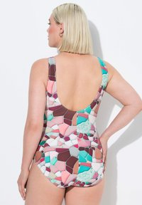 Maillot de bain une pièce avec un motif de mosaïque multicolore dans des tons de rose, bleu canard et marron, doté d'un dos plongeant et de larges bretelles.
