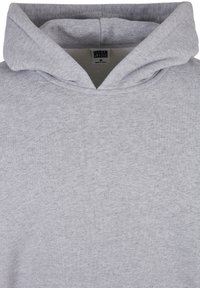 Felpa con cappuccio grigia realizzata in un morbido tessuto. Presenta un ampio cappuccio e un collo a coste con texture. Etichetta visibile all'interno con informazioni sul marchio.