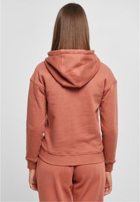 Sudadera con capucha en rosa empolvado, hecha de una mezcla de algodón. Cuenta con puños y dobladillo acanalados, con un ajuste relajado y una textura suave.