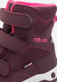 Vyniojamas bordeaux spalvos vandeniui atsparus botukas su rožinėmis detalėmis, turintis tinklelio viršutinę dalį, dvi Velcro juostas ir tekstūruotą paviršių su logotipo detale.