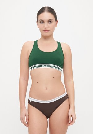 Grønn bomulls sports-bh med hvit og grønn stripete kant; paret med brune truser med hvit elastisk midjebånd og logodetalj.