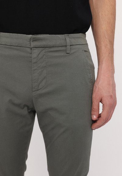 Pantaloni gri dintr-un amestec de bumbac, cu o croială slim, având buzunare frontale, paspoale pentru curea și o textură netedă. Vedere detaliată care accentuează talia și mâna.
