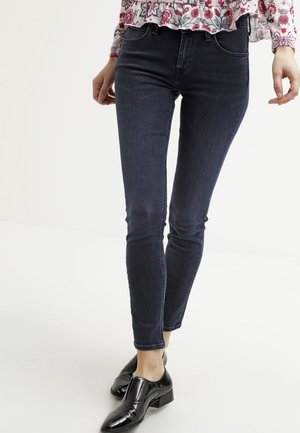 Jeans ajustados de color azul oscuro, fabricados en denim, con un corte elegante, diseño de cinco bolsillos y mínimos acentos en hardware.