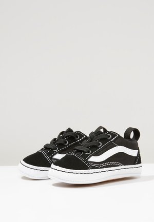 Sort-hvide småbørns sneakers med snørebånd, hvidt syet design og trækstropper på en ensartet lys baggrund.