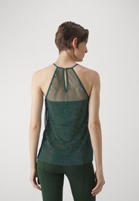 Netting tank top i mørkegrønn med drapert rygg, med halterneck-design og en nøkkelhulldetalj på baksiden. Glatt tekstur gjennom hele.