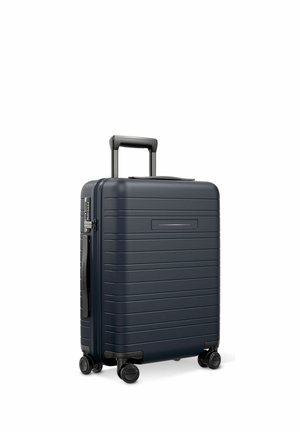 Dark blue hard-shell suitcase with horizontal ridges, four spinner wheels, telescopic handle, and side handle on a white background.