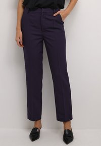Pantalons tailleur violets avec une coupe droite, dotés d'un devant plat, de poches latérales et d'une texture de tissu lisse. Ballerines noires à bout pointu.