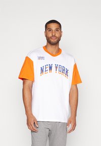 Fehér póló narancssárga rövid ujjakkal, kék színű "NEW YORK" felirattal, és "NYC" logóval a bal vállon. Pamut anyag, kerek nyakú fazon.