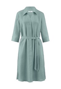 Hellgrünes Leinenhemdkleid mit Kragen, langen Ärmeln und einem Stoffgürtel, versehen mit seitlichen Schlitzen für Komfort und Bewegungsfreiheit.