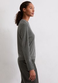 Szary longsleeve w dopasowanym kroju, wykonany z miękkiego materiału o gładkiej fakturze. Posiada okrągły dekolt oraz subtelne prążkowanie u dołu.