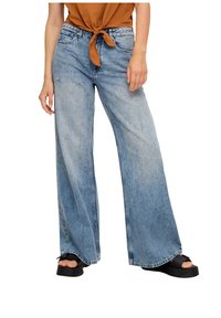 Ljusblå vida jeans i denim med rå fåll, som har en avslappnad passform och diskreta slitna detaljer. Kombinerade med en brun knuten topp.