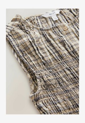 Top senza maniche con bottoni realizzato in tessuto leggero e testurizzato, con una base beige e un motivo a quadri in tonalità di marrone scuro e blu.