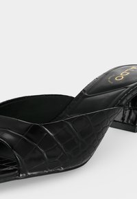 Sandale à talon ouverte style mule noire avec dessus en cuir embossé effet croco et semelle intérieure rembourrée portant la mention "ALDO".