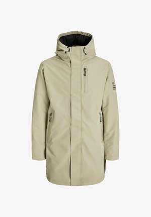 Bēša ūdensizturīga jaka ar kapuci, ar rāvējslēdzēju priekšpusē un sānu kabatām. Iezīmēta ar melnu iekšējo oderi un logo detaļu uz piedurknes.