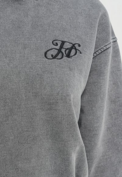 Felpa grigia con tessuto texturizzato, caratterizzata da un logo ricamato nero sul petto. Il design include un collo a giro e una vestibilità comoda.