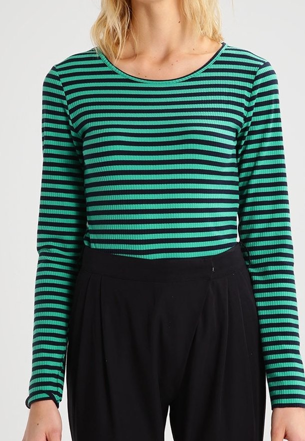 Grün und schwarz gestreifte Langarmbluse mit geripptem Muster und rundem Ausschnitt, kombiniert mit hochtaillierten schwarzen Hosen.