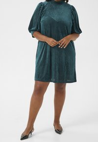 Teal samettimini mekko, jossa on pystysuorat raidat, korkea kaula-aukko ja puffihihat. Sujuva rakenne ja rento leikkaus korostavat suunnittelua.