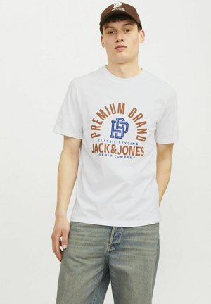 Hvid bomulds T-shirt med et multicolor logo med "JACK & JONES" og mønstrede detaljer. Sammen med lyse denim bukser.