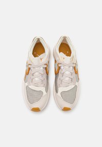 Keve sneakers, jotka ovat valmistettu verkkokankaasta ja mokasta beigen ja oranssin yhdistelmässä, jossa on ruudullinen kuvio, nauhakiinnitys ja pehmustettu kaulus.