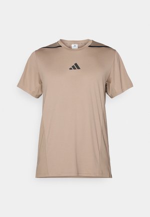 T-shirt de sport tan fabriqué dans un tissu lisse, avec des accents noirs sur les épaules et un logo Adidas noir centré sur la poitrine.