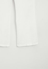 Hem and lower portion of plain white straight-leg pants against a neutral background.