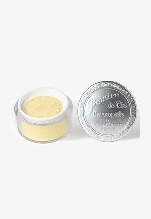 Translucent jar of pale yellow powder next to a silver, embossed lid. The lid features decorative edging and text.